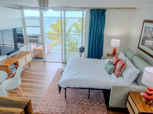 a bedroom with a bed and a living room with a balcony at Beachfront Studio w Amazing Views in Hauula