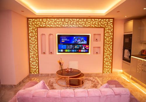 a living room with a couch and a tv on a wall at Velmora Apartments in Huddersfield