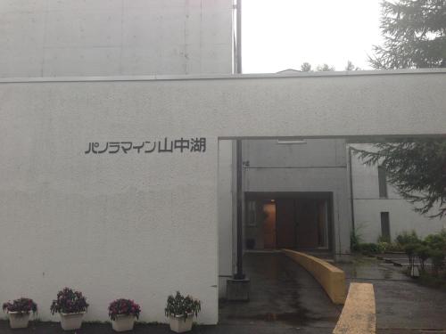 a white building with a sign on the side of it at Panorama Inn Yamanakako in Yamanakako