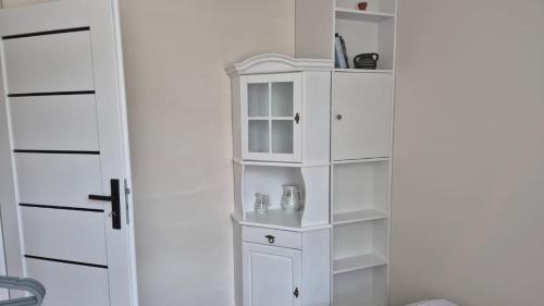 a white book shelf next to a white cabinet at Pension Etiuda in Duszniki Zdrój