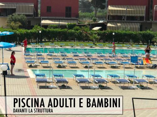 ein Swimmingpool mit blauen Stühlen und einer Gruppe von Menschen in der Unterkunft Pine Beach House - Villaggio Turistico con Piscina e Animazione in Campofelice di Roccella