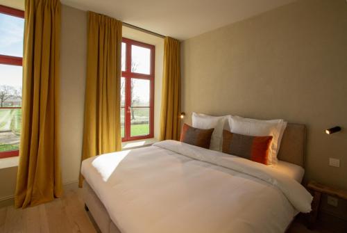 a bedroom with a large white bed and a window at De Snippe in Damme