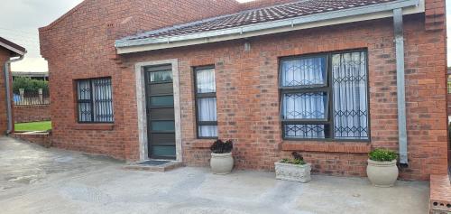 马塞卢AuusiMA Family Stay的一栋砖房，有三扇窗户和几盆植物。