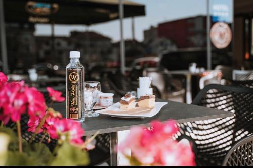 ein Tisch mit einem Teller Desserts und einer Flasche Wasser in der Unterkunft New Hotel in Sarajevo