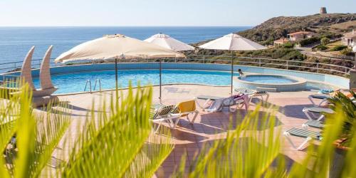 een zwembad met stoelen en parasols en de oceaan bij Zeeva Hotel and Resort in Torre Dei Corsari