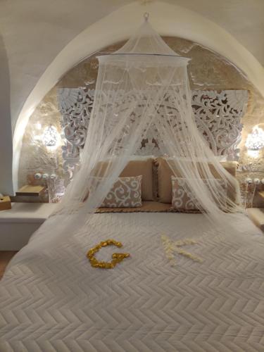 a white bed with a canopy with a gold number on it at Victoria's Home in Faccia di Trippa