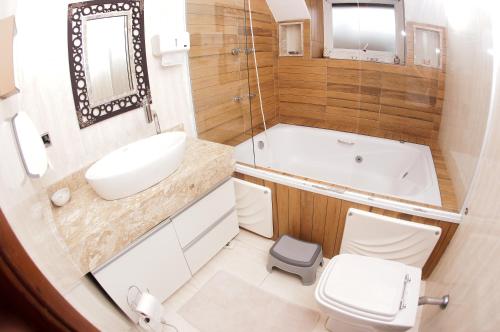 a bathroom with a tub and a sink and a toilet at Castelinho Solemar - Suíte Premium com Banheira Privativa e Ar in Praia Grande