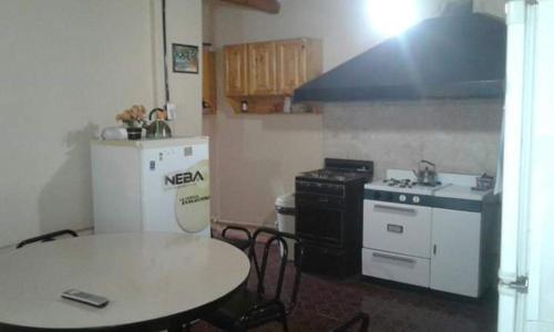 una cucina con un tavolo, un fornello e un frigorifero di La comarca hostel a San Luis