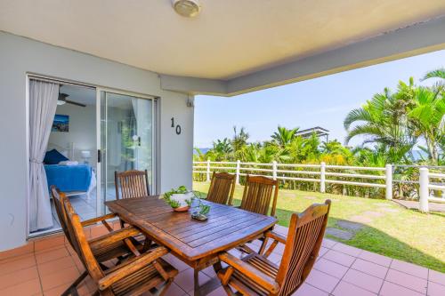 a wooden table and chairs on a patio at Sea-Renity 10 in Umdloti