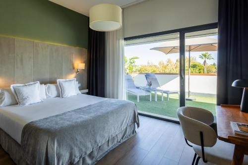 a hotel room with a bed and a desk and a window at Sevilla Green Suites in Alcalá de Guadaira