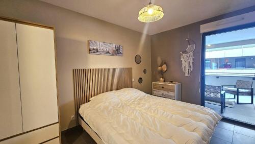 een slaapkamer met een bed, een tafel en een raam bij Appartement Standing 5mn Village de Noël in Le Barcarès