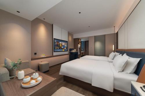 長沙市にあるMEHOOD LESTIE HOTEL- Changsha South Sation Branchの大きなベッドとリビングルームのある寝室