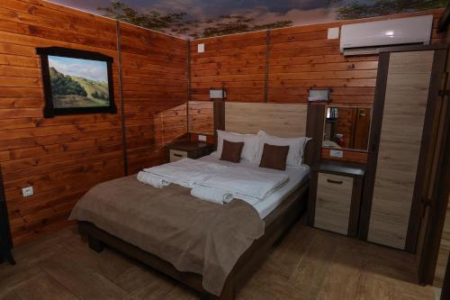 a bedroom with a bed in a room with wooden walls at Cuki Residence in Mala Ravna Reka
