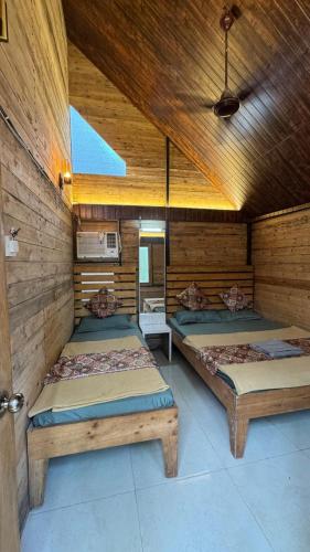 a room with two beds in a wooden room at Nature's Wood in Matheran
