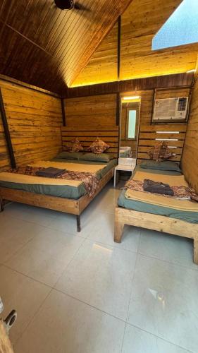 two beds in a room with wooden walls at Nature's Wood in Matheran
