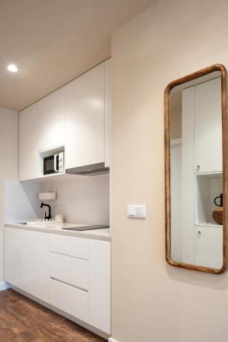 a kitchen with white cabinets and a mirror at Foz Apartments & Suites in Figueira da Foz