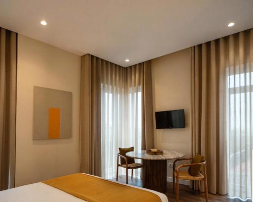 ein Hotelzimmer mit einem Bett, einem Tisch und einem Fernseher in der Unterkunft Foz Apartments in Figueira da Foz