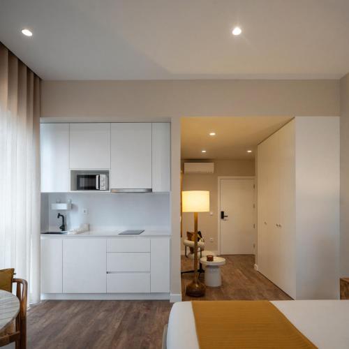 a bedroom with white cabinets and a kitchen at Foz Apartments in Figueira da Foz