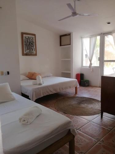 a white room with three beds and a window at Casa del Alma in Puerto Escondido