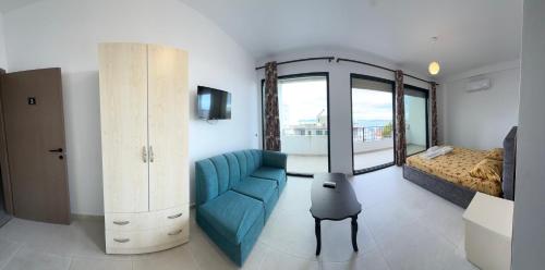 een woonkamer met een blauwe bank en een bed bij Actium in Vlorë