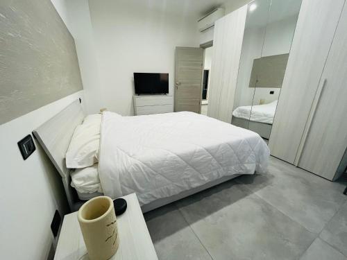 Un dormitorio blanco con una cama y un televisor. en Milano Bicocca Apartment & Rooms2, en Cinisello Balsamo