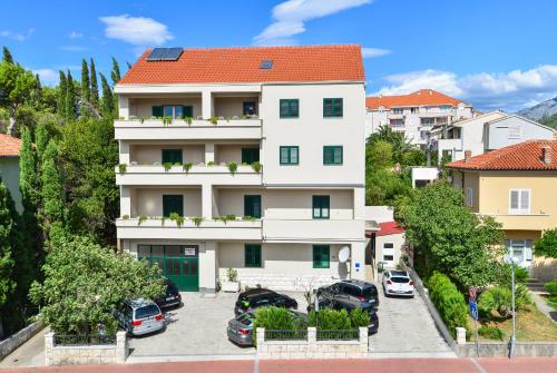 an apartment building with cars parked in a parking lot at Apartments Elda in Makarska