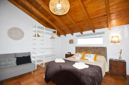 een slaapkamer met een bed en een bank bij Book Jet - Villa Malpai with private pool jacuzzi in Roque