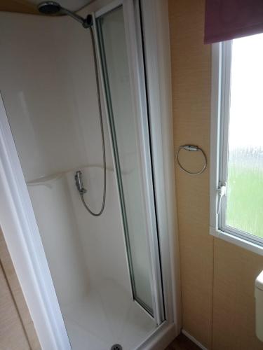 a glass shower in a bathroom with a window at The Franklin in Saint Osyth