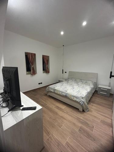 La Dimora di Bacco في Sannicandro di Bari: غرفة نوم مع سرير وتلفزيون بشاشة مسطحة