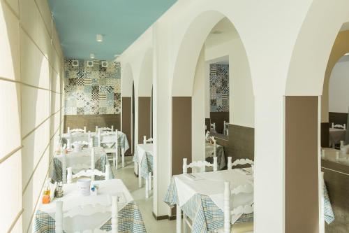 a restaurant with white tables and white chairs at Hotel Biancaneve Wellness in Marotta