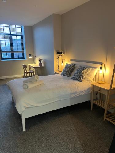 a bedroom with a large white bed with two tables at Chic Mill conversion beside Piece Hall & Eureka! in Halifax