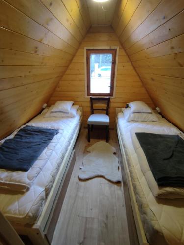 two beds in a wooden room with a window at Mókuslak Mátra in Mátraszentimre