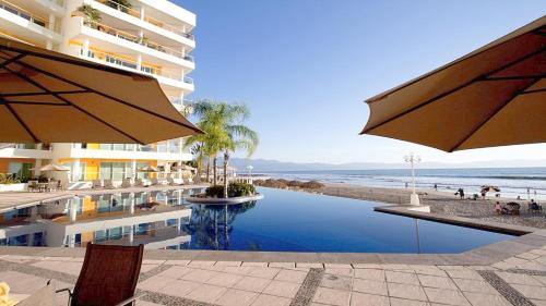 a hotel with a swimming pool next to the beach at Condo Vela Vista 1004 by Kivoya in Nuevo Vallarta
