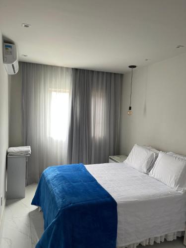 a bedroom with a large bed and a window at Itapuã Beach - Espaço Aconchegante e Tranquilo pra você e sua família! in Salvador