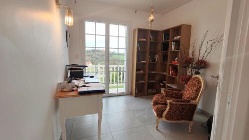 Habitación con escritorio, silla y ventana. en Cosy Orchidée - Villa Élégance, Piscine & Pyrénées "5 étoiles", en Baigts-de-Béarn