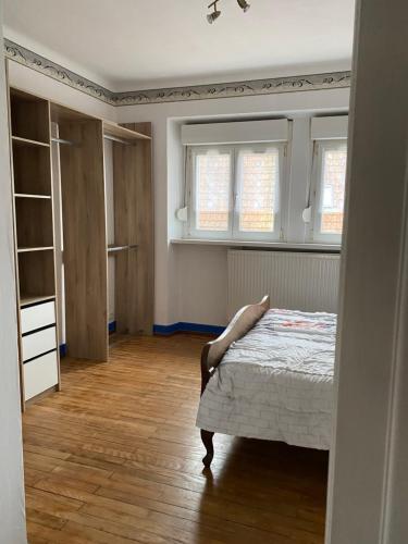 a bedroom with a bed and two windows at La Maison des Pierres in Zinswiller