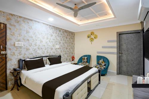 Townhouse Shri Mahakaleshwar Jyotirlinga Ujjain Formerly Hotel Shikhar Darshan في اوجاين: غرفة نوم بها سرير كبير وكراسي زرقاء