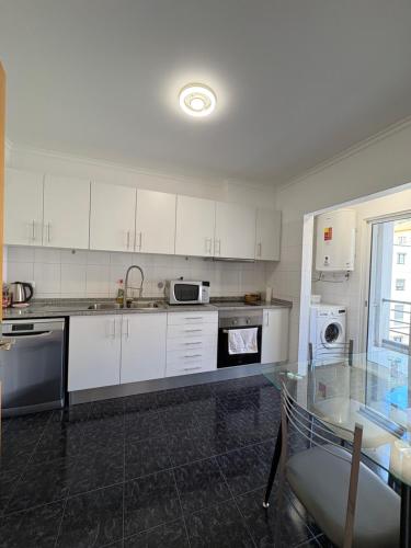 una cucina con armadi bianchi e tavolo in vetro di Island Heart- Family Retreat- Free parking garage a Ribeira Brava