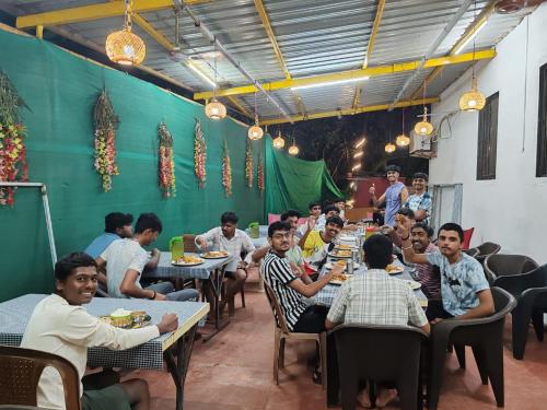 马尔万Konkan Paradise-Siddhivinayak,Devbag Beach Resort的一群人坐在餐厅的桌子旁