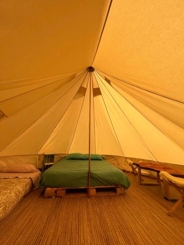 a tent with a bed and a table in it at Glamping Peumayen carpintero in Llanquihue