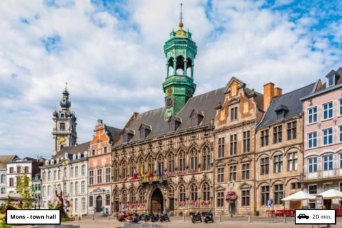 a large building with a clock tower on top of it at Les Campanes - Gîte Wellness 8 pers avec Piscine intérieure & Sauna - Proche Mons 