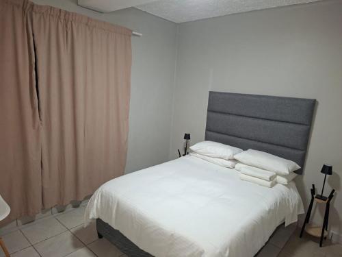 Grace Villas 3 في شرق لندن: غرفة نوم بها سرير مع ملاءات ووسائد بيضاء