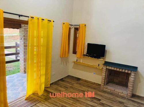 un soggiorno con tende gialle e camino di Chale Manticas aconchego na Serra da Mantiqueira a Costas