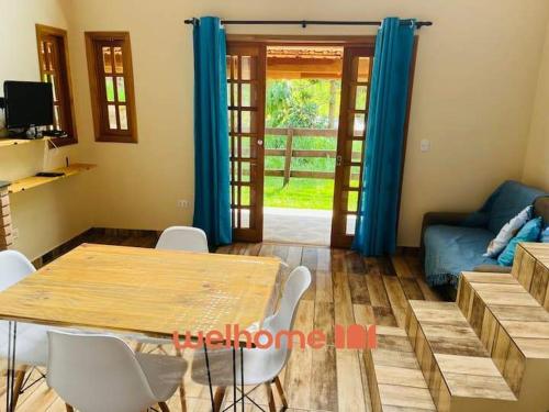 un soggiorno con un tavolo di legno e sedie bianche di Chale Manticas Blue na Serra da Mantiqueira a Córrego do Bom Jesus