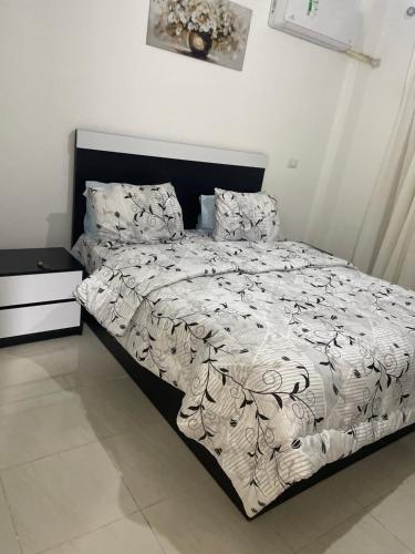 a bed with a black and white comforter and pillows at Madinaty golden stay in Madinaty