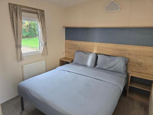a bedroom with a large bed with a wooden headboard at Laguna- Rockley Park Poole in Poole
