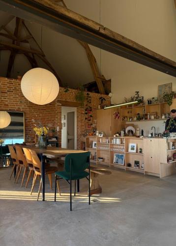 una sala da pranzo con tavolo e sedie e una cucina di Grange transformée a Crucheray