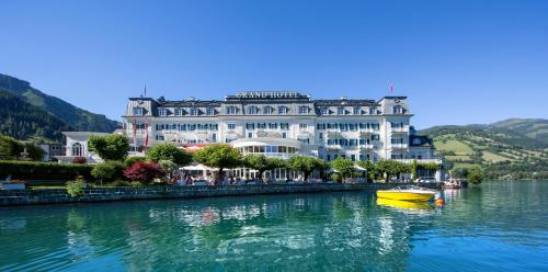 a yellow boat in the water in front of a building at Grand Hotel Zell am See in Zell am See