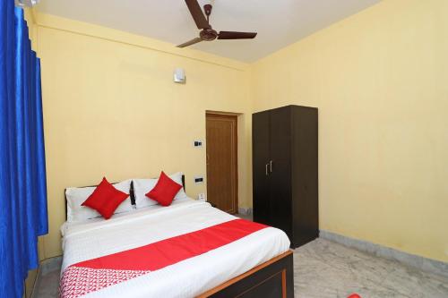 OYO Hotel O Maa Tara Guest House في Jādabpur: غرفة نوم بسرير ومخدات حمراء وسقف