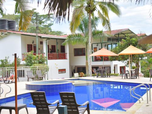 a pool with chairs and umbrellas in front of a house at Ecohotel Monteverde in La Vega